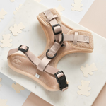 Beige pet harness with black straps on a light background