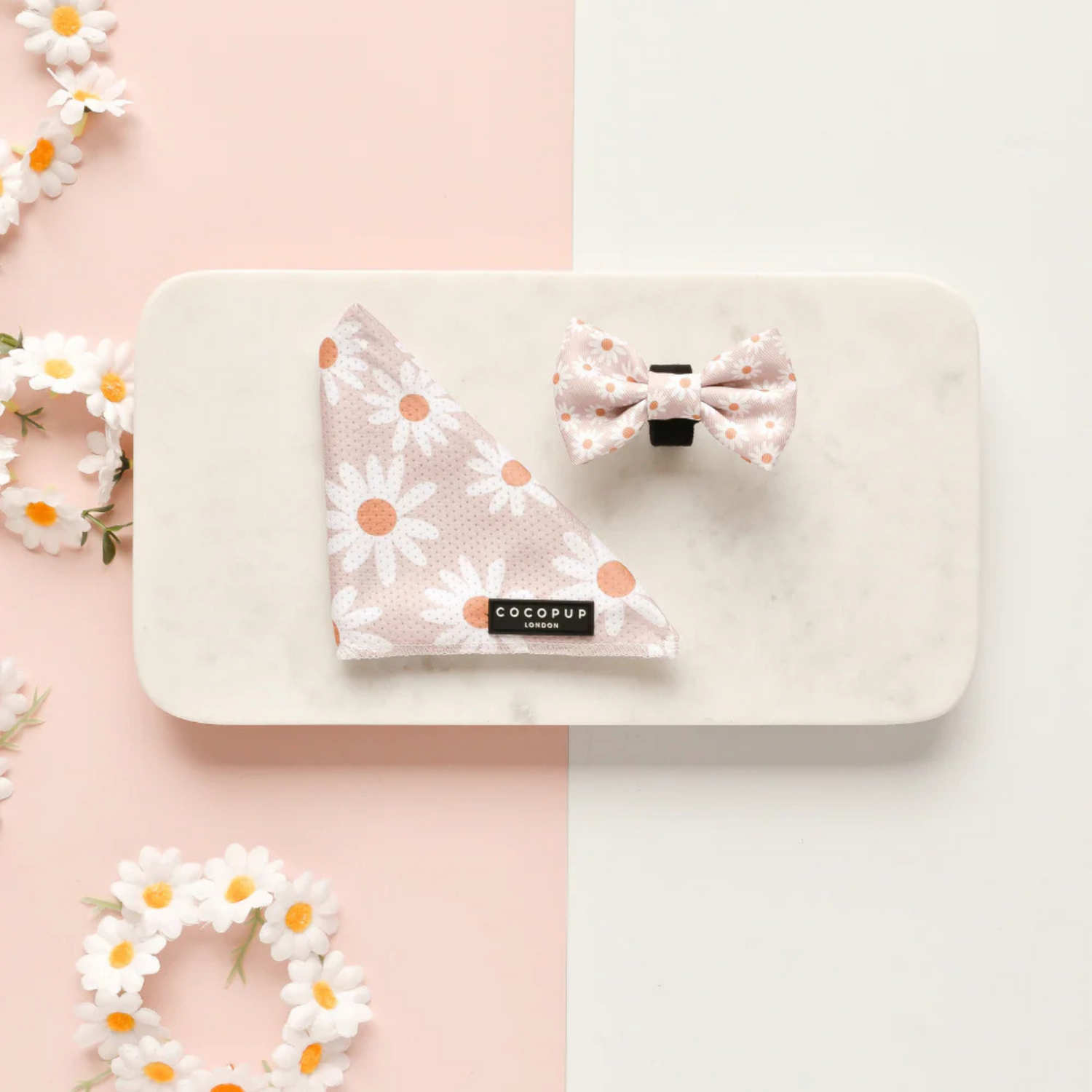 Floral-patterned dog bandana and bow tie on a white tray with a pink background