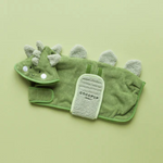 Green dinosaur-shaped towel with a small paddle on a light green background