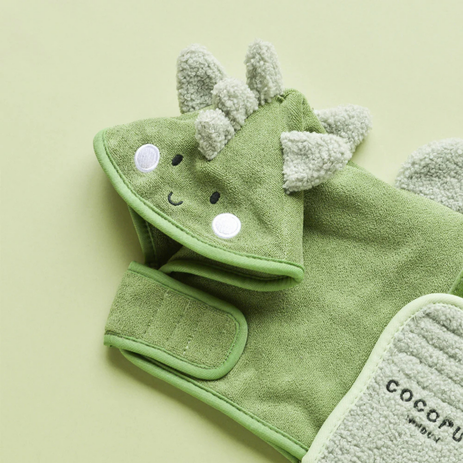 Green dinosaur-themed towel with matching hat on a light green background
