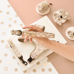 Cocopup dog collar and leash set held by a hand on a decorative background with small white flowers.