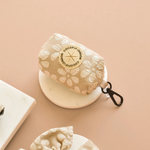 Floral-patterned pouch with a brand logo on a beige background