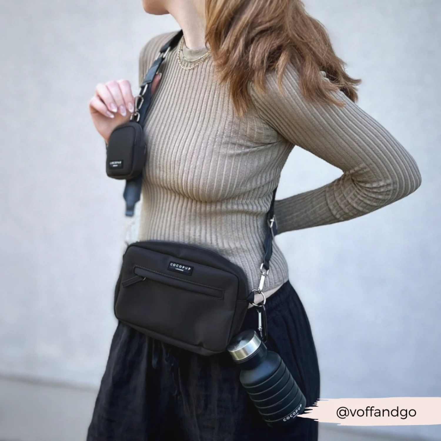 Person wearing a black crossbody bag with a water bottle holder, against a plain background.