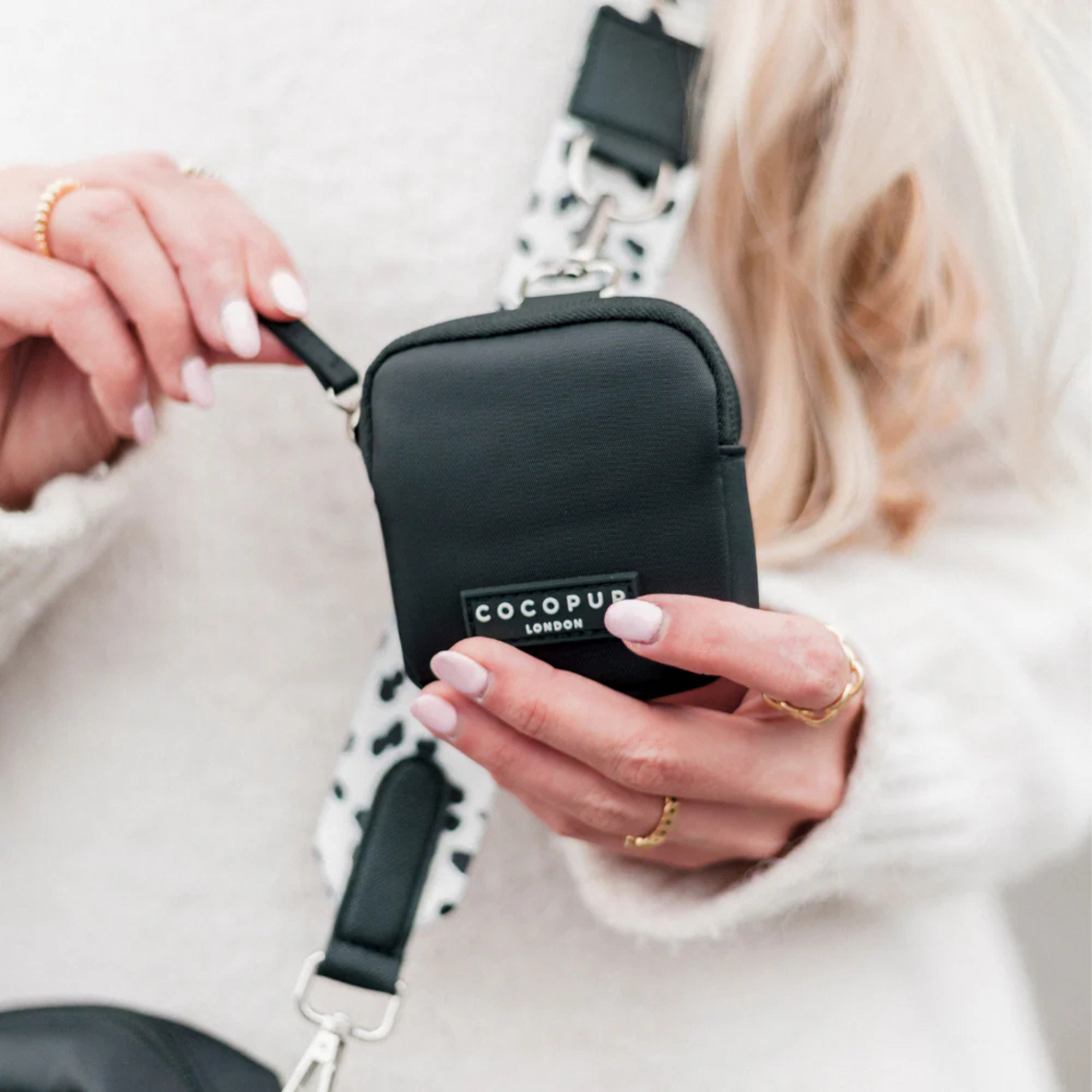 Person holding a black COCOPUP bag with a blurred background