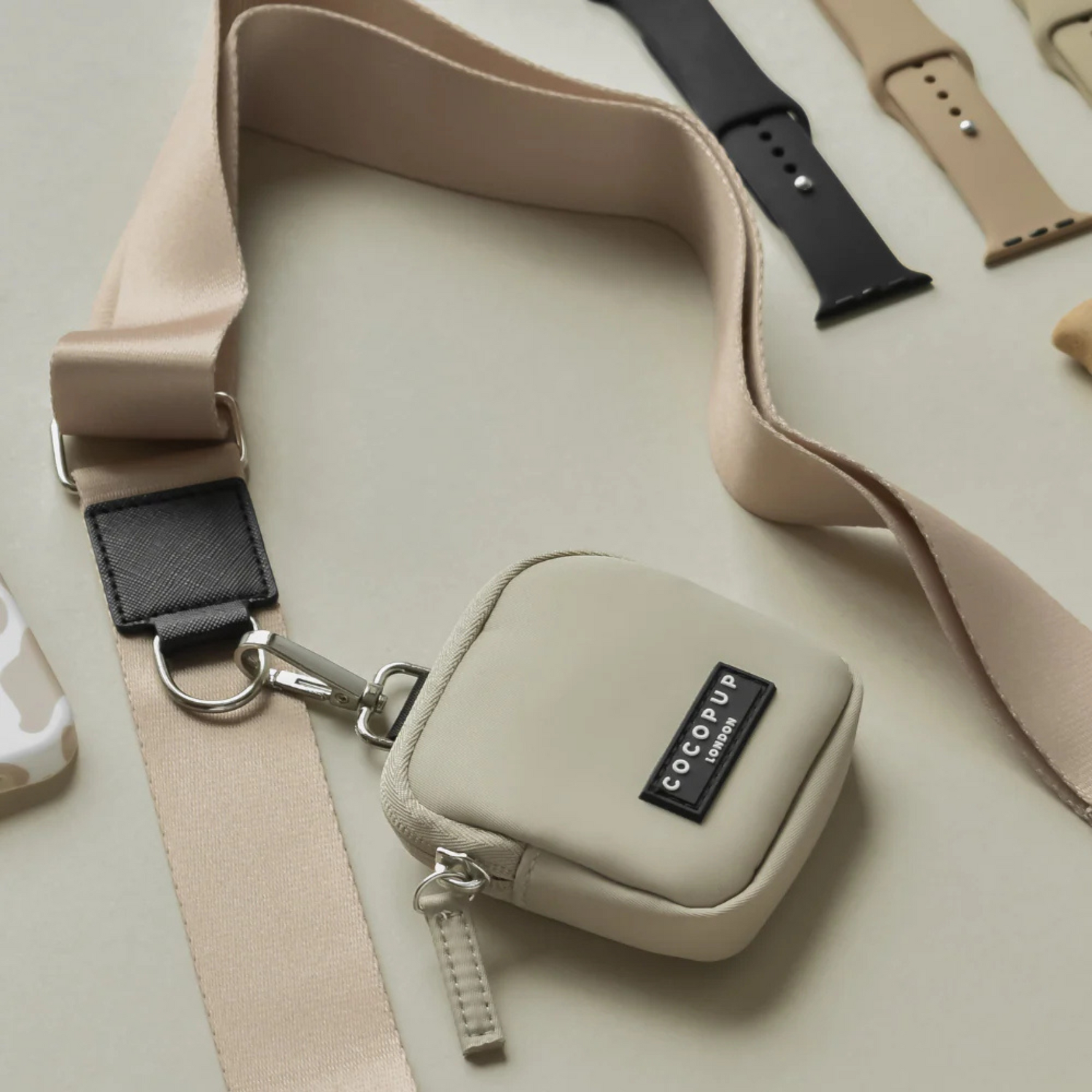 Small beige pouch with a strap and COCOPUP branding on a light background