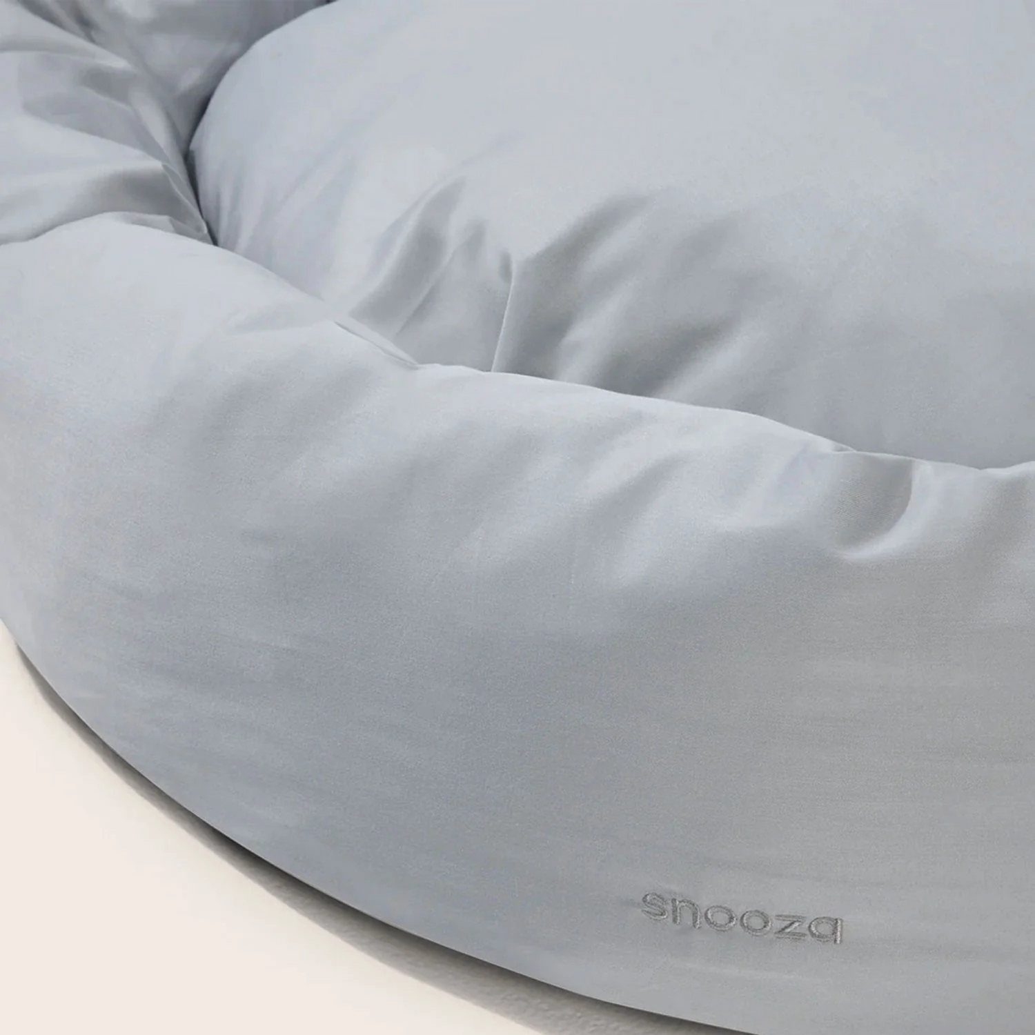 Grey dog bed with 'Snoozza' branding on a light background