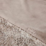 Close-up of a beige blanket with textured edge and brand logo.
