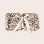Fluffy blanket with a ribbon on a beige background