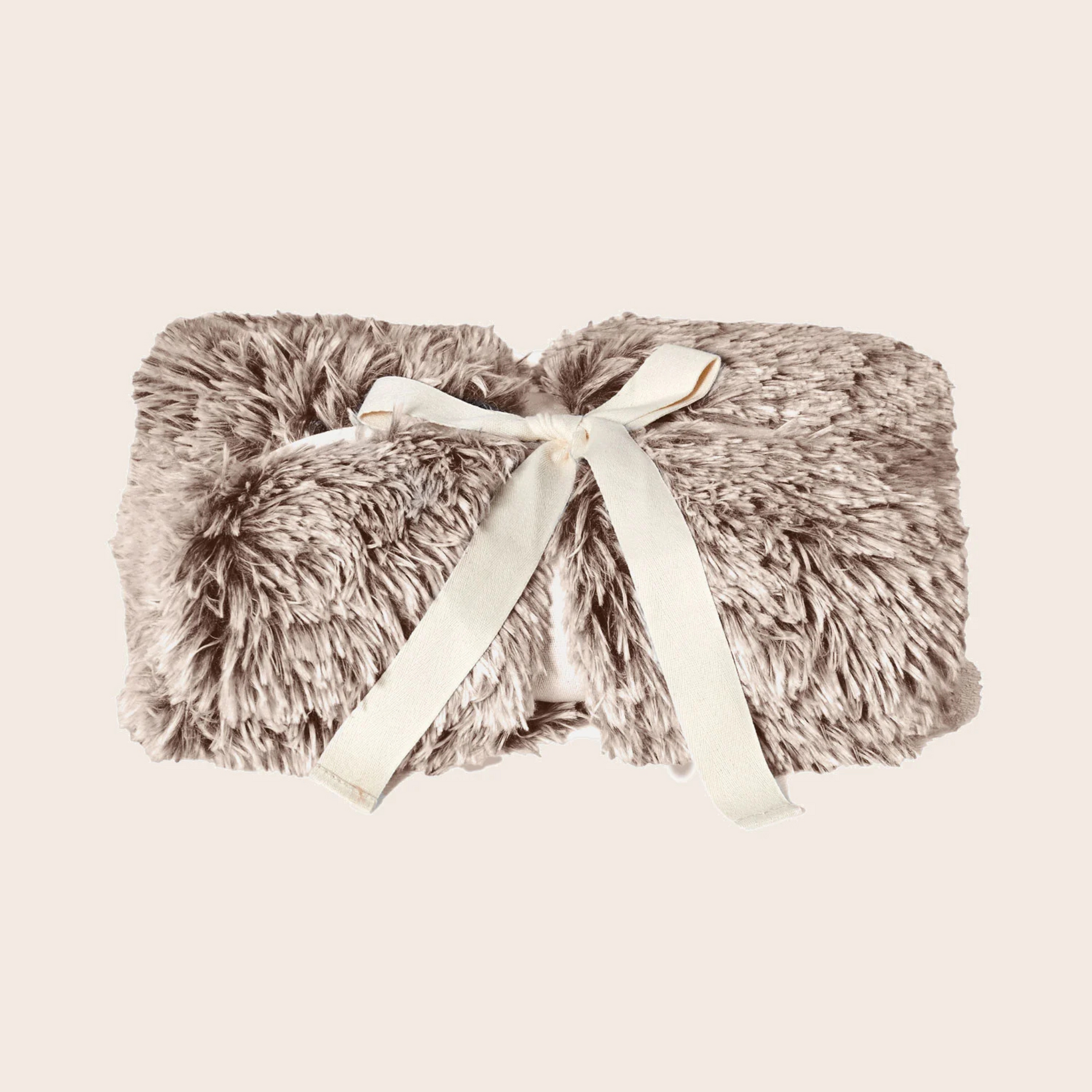 Fluffy blanket with a ribbon on a beige background