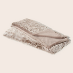 Folded blanket with fur trim on a light beige background
