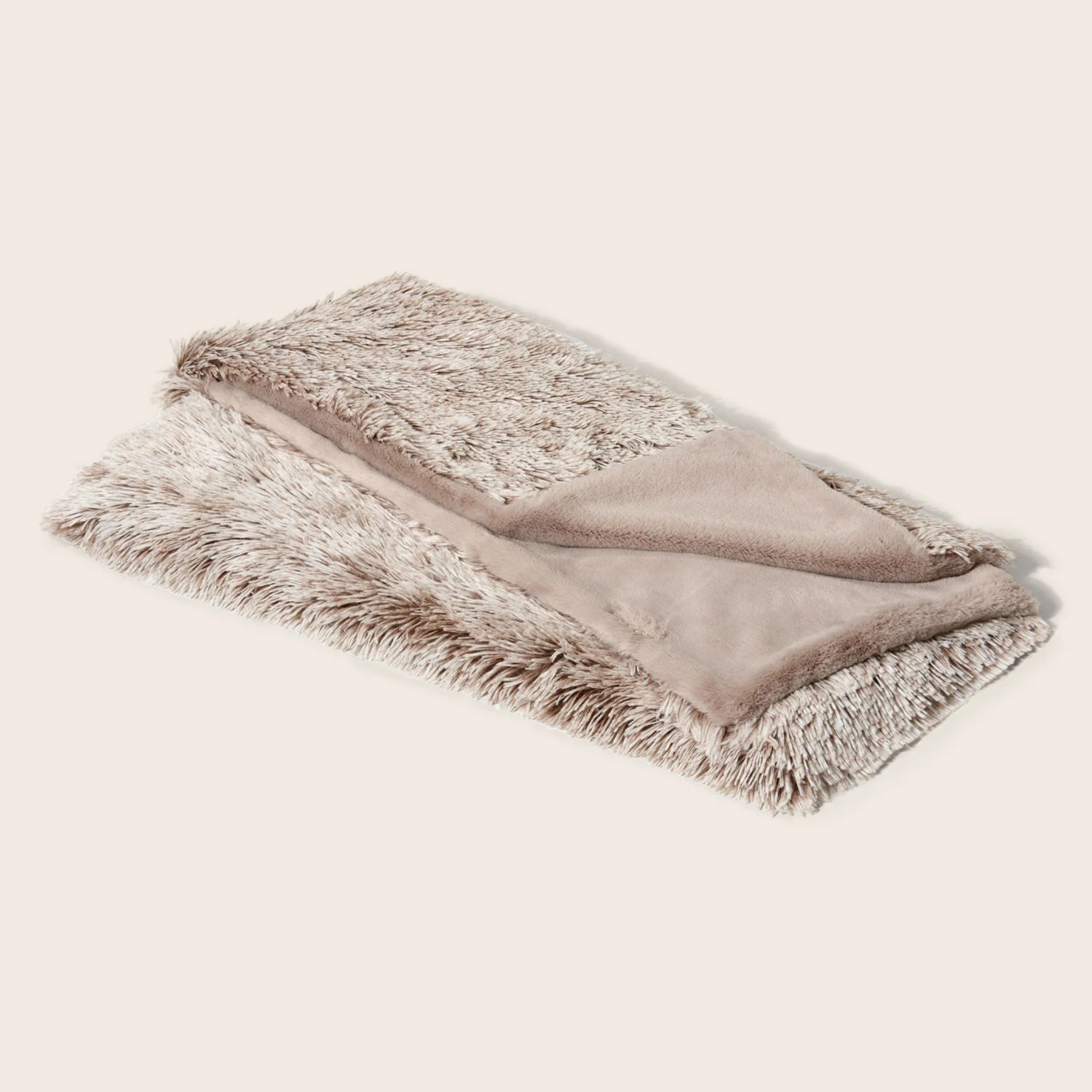Folded blanket with fur trim on a light beige background