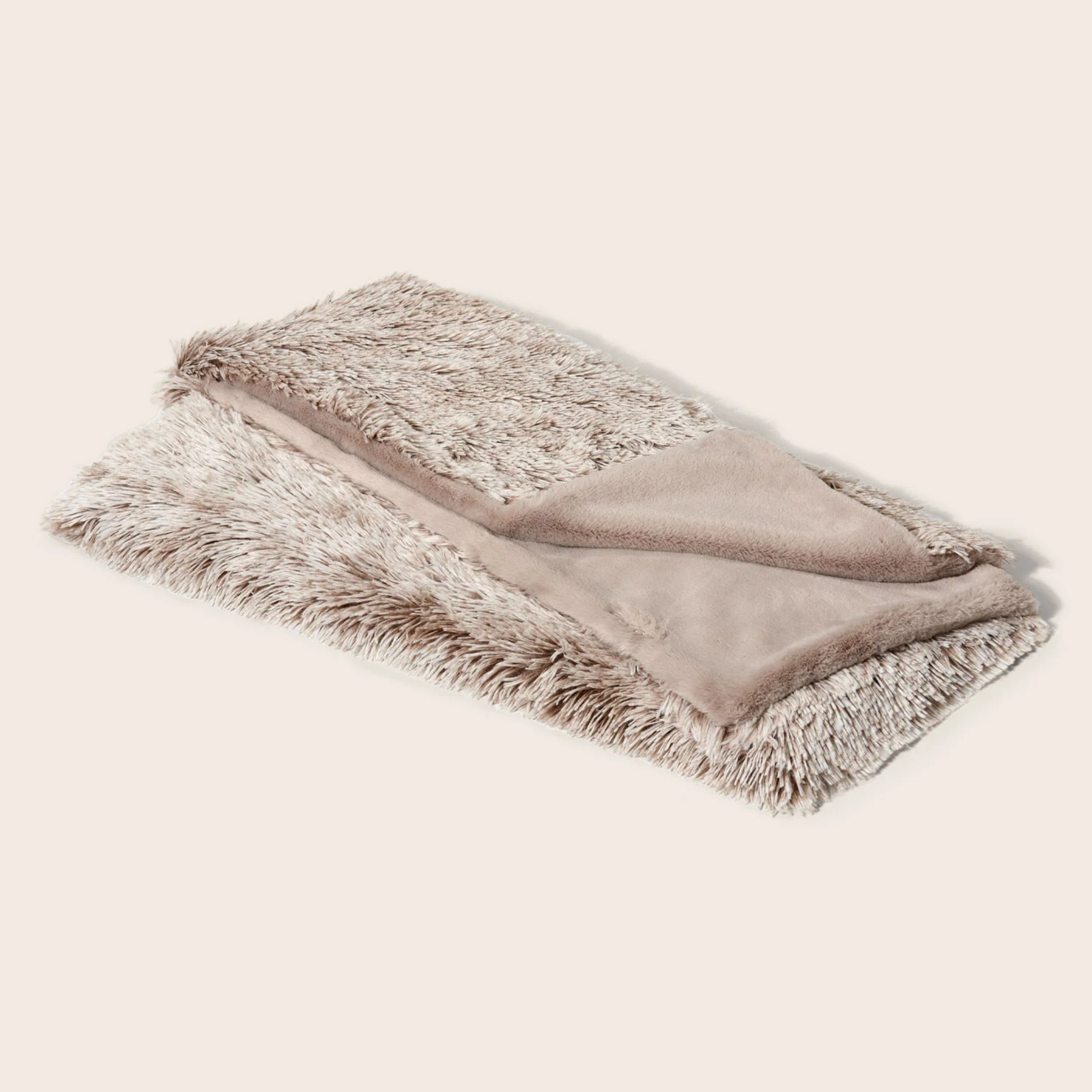 Folded blanket with fur trim on a light beige background