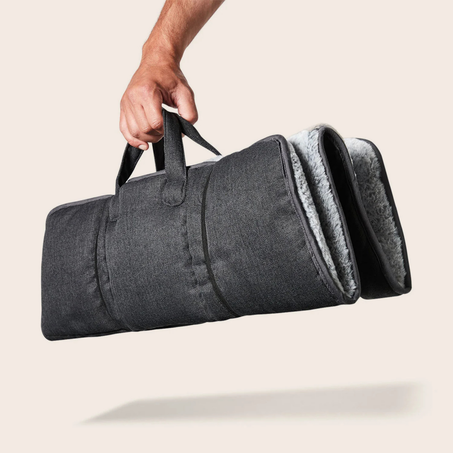 Person holding a grey folded travel mat against a beige background