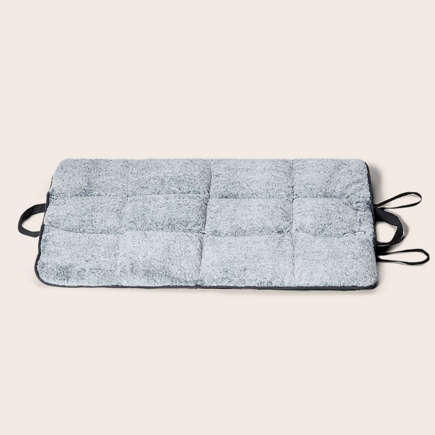 Gray quilted mat with black straps on a beige background